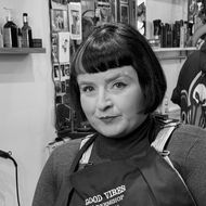 Betsy Miller sitting in her barber chair facing the camera, an imposing look upon her face