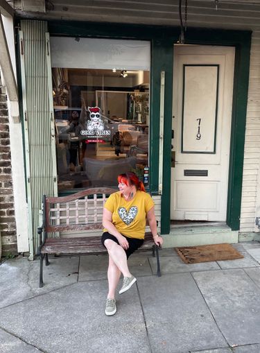 The exterior of Good Vibes Barbershop, the owner Sarah relaxing on the bench outside